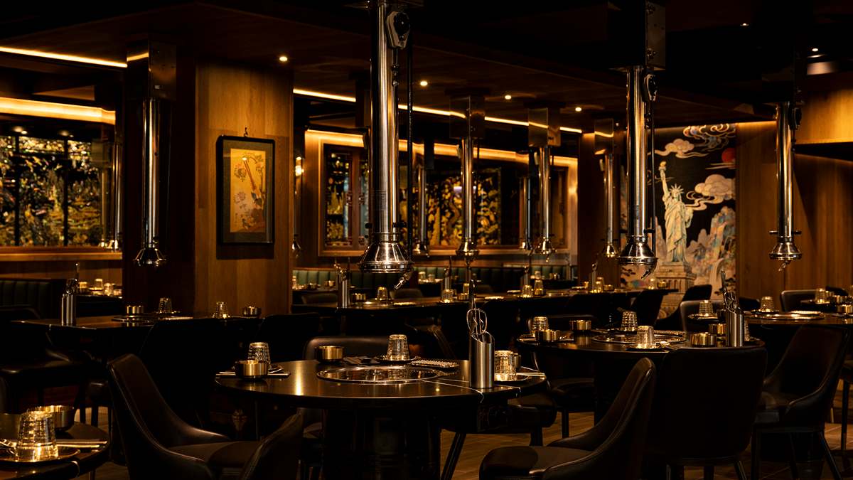 Dark Baekjeong Black dining room with steel grill hoods, black tables, and a Statue of Liberty panel