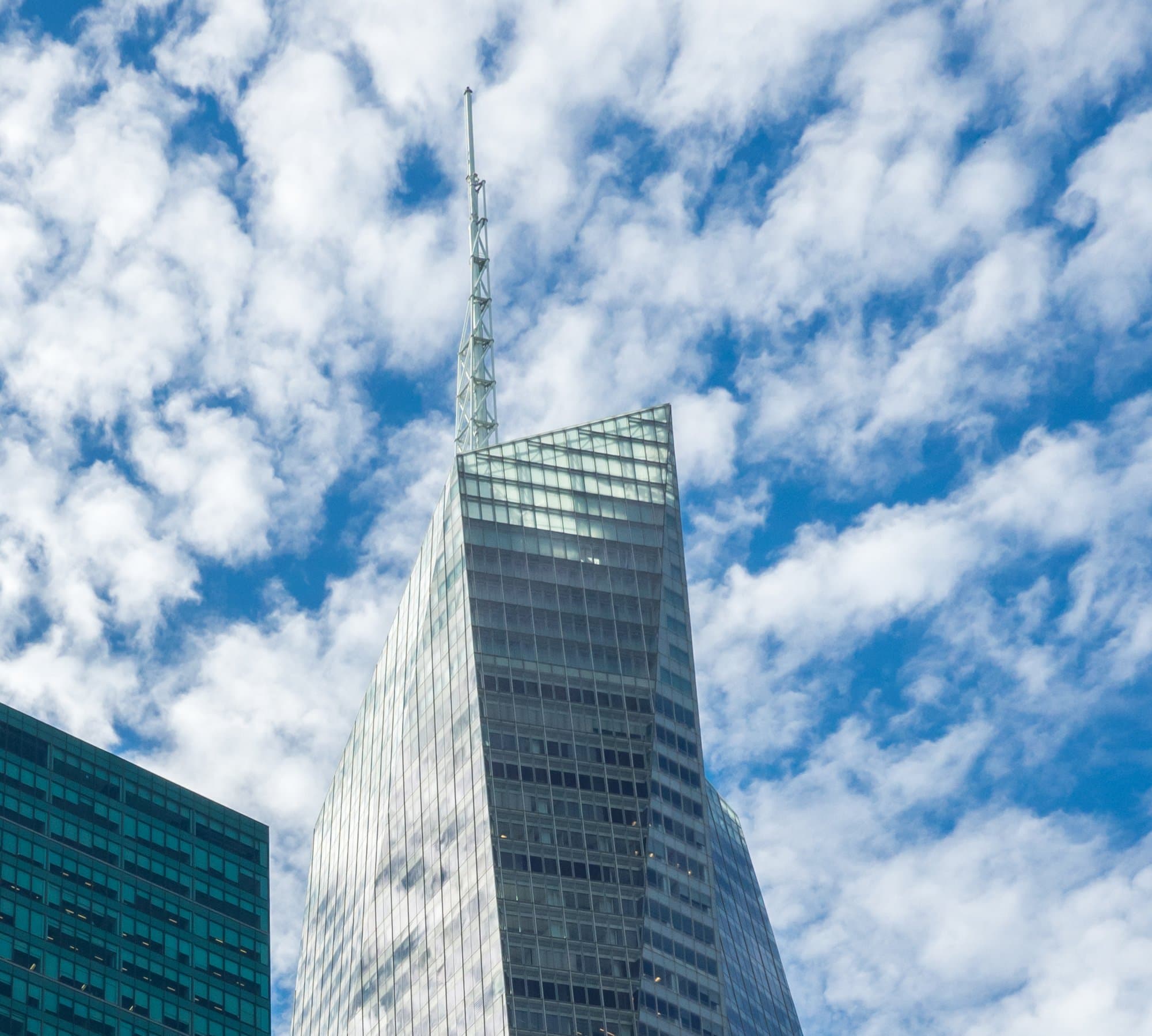 The glass crown and spire of the Bank of America Tower against a blue sky