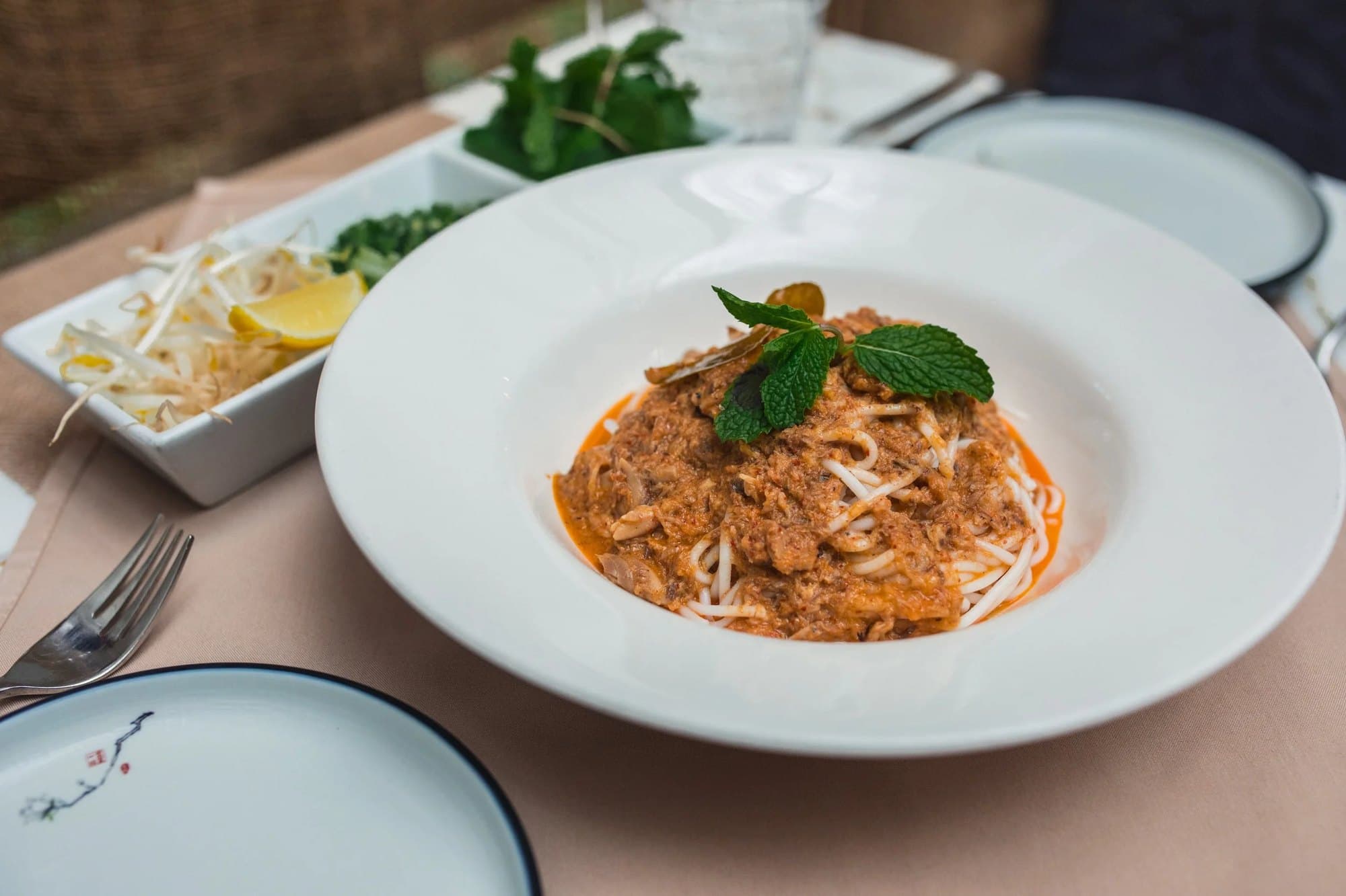 Bowl of Bayon nyoam rice noodles with fish curry gravy and mint