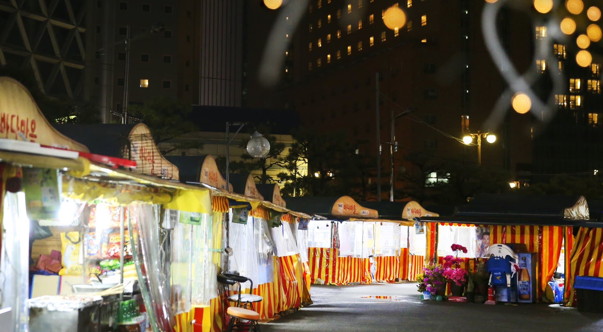 Night row of striped pojangmacha tents with Hangul signs in Haeundae, Busan