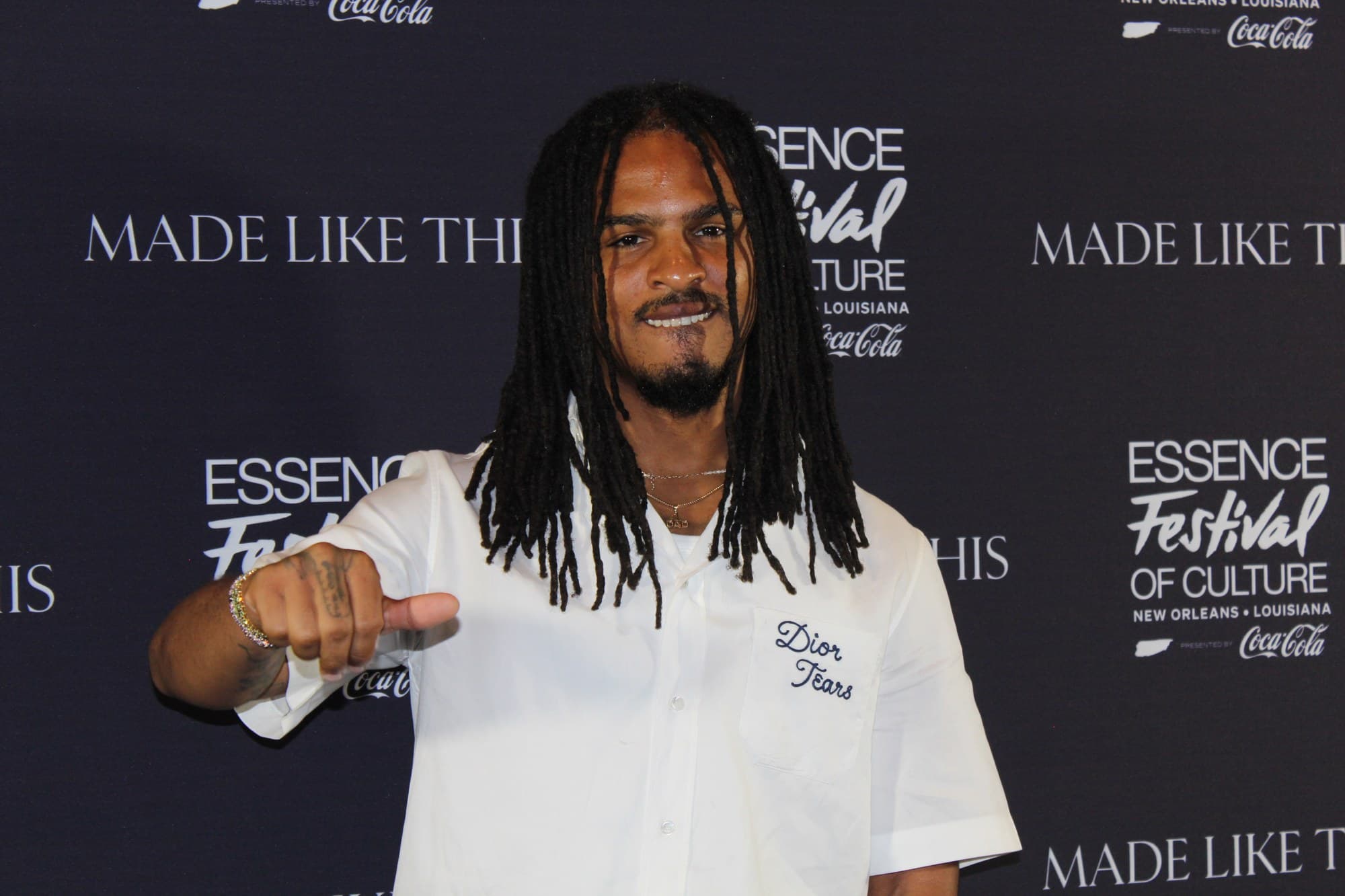 Keith Lee smiling in a white shirt, pointing toward the camera, at the Essence Festival of Culture