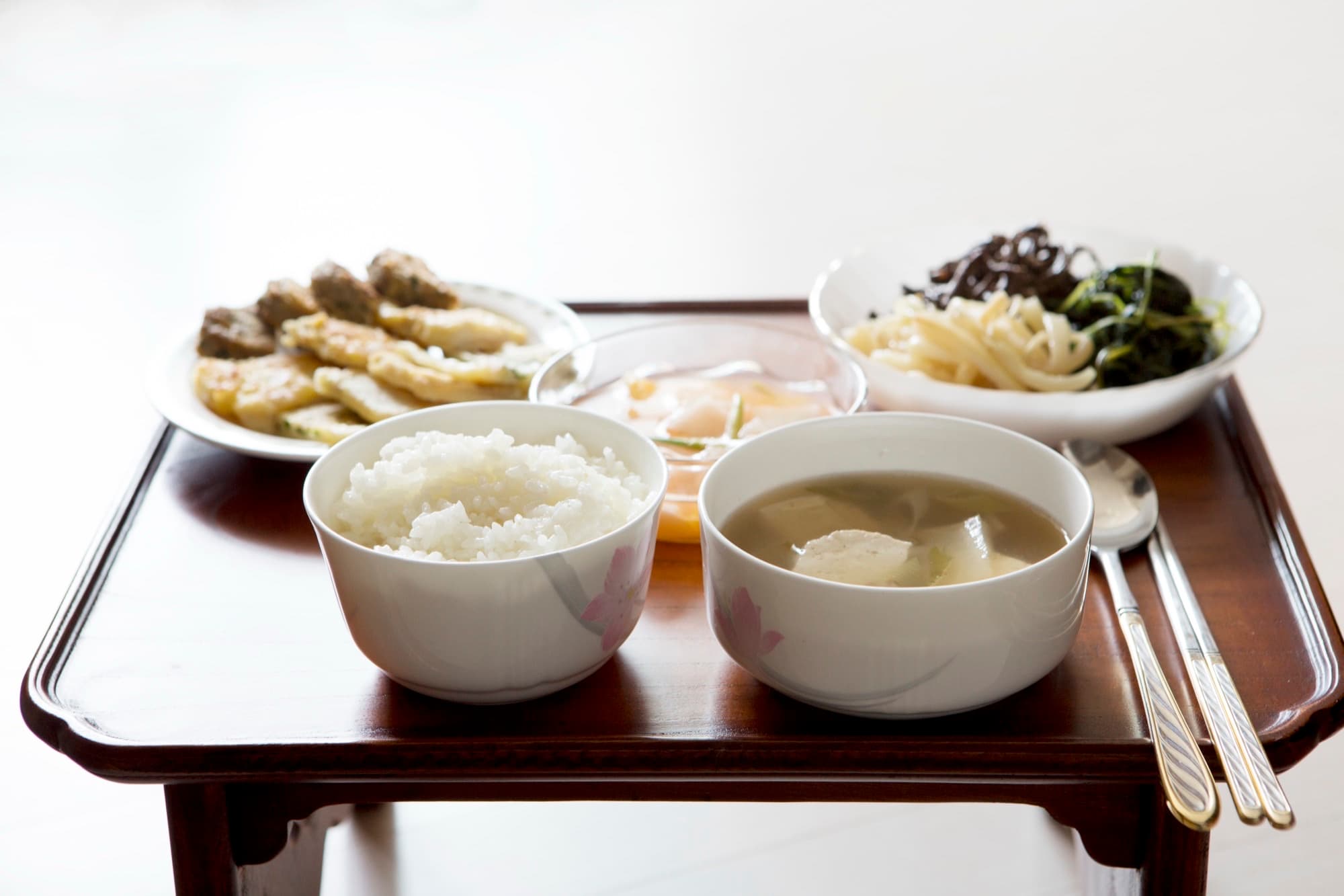 Korean bapsang table with rice, soup, namul vegetables, and jeon on a low wooden tray table