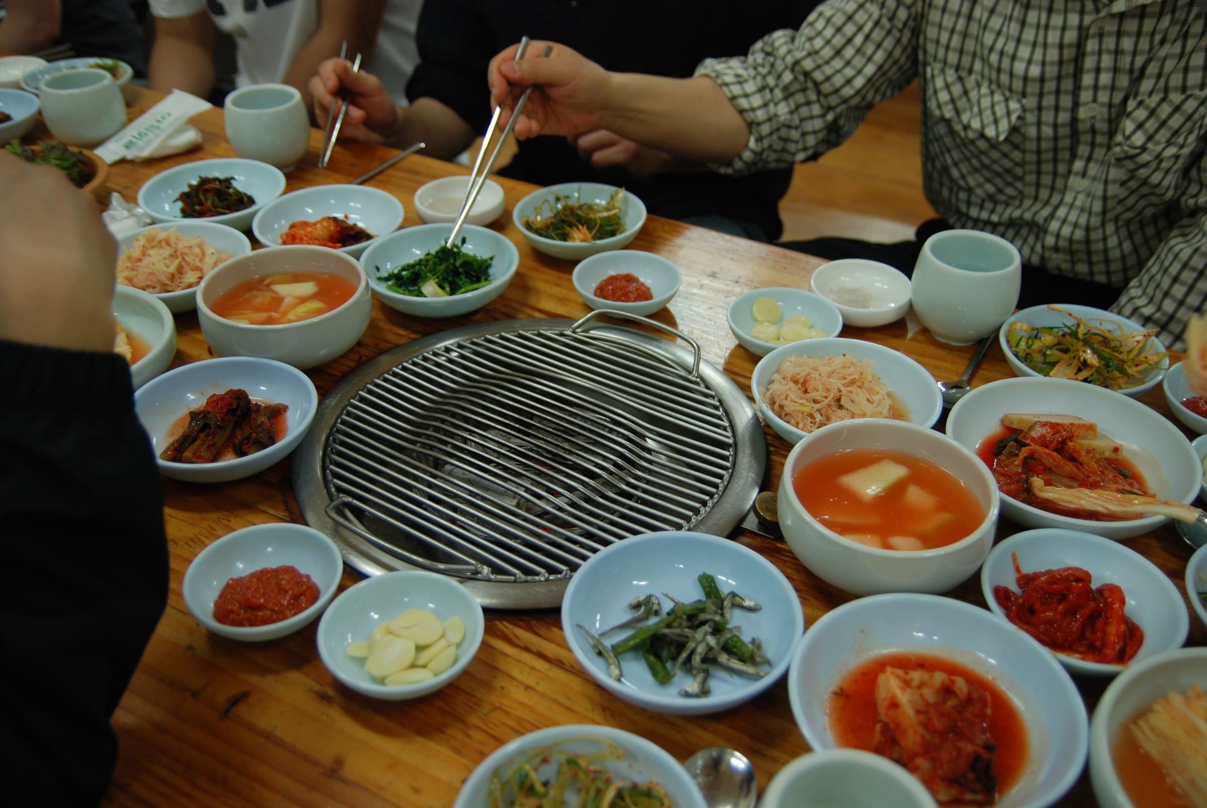 Tabletop Korean barbecue grill surrounded by bowls of banchan