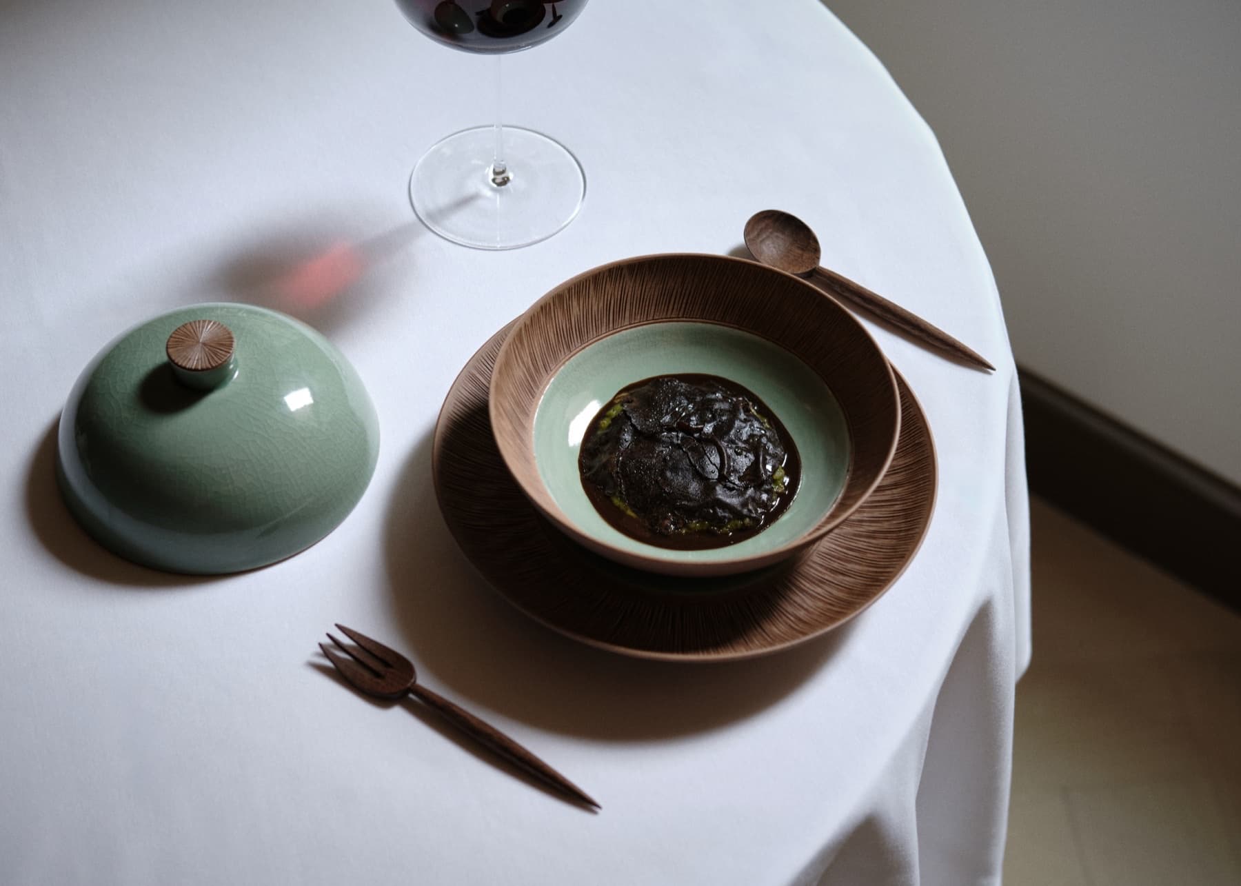 Spring green porridge under soy-preserved black truffle with wooden utensils and celadon cloche at Oyatte