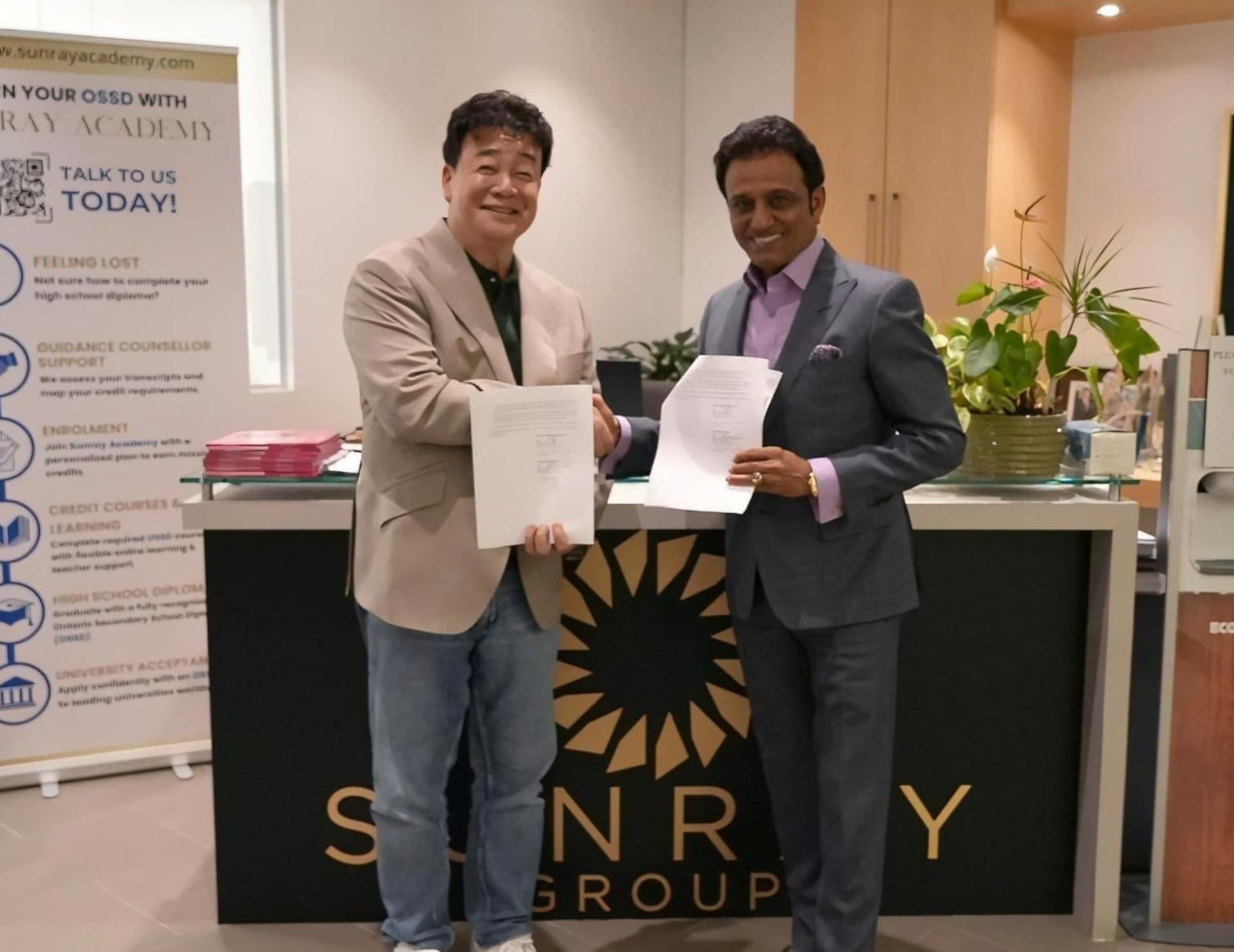 Paik Jong-won and Rattan Gupta shake hands over a Sunray Group reception desk