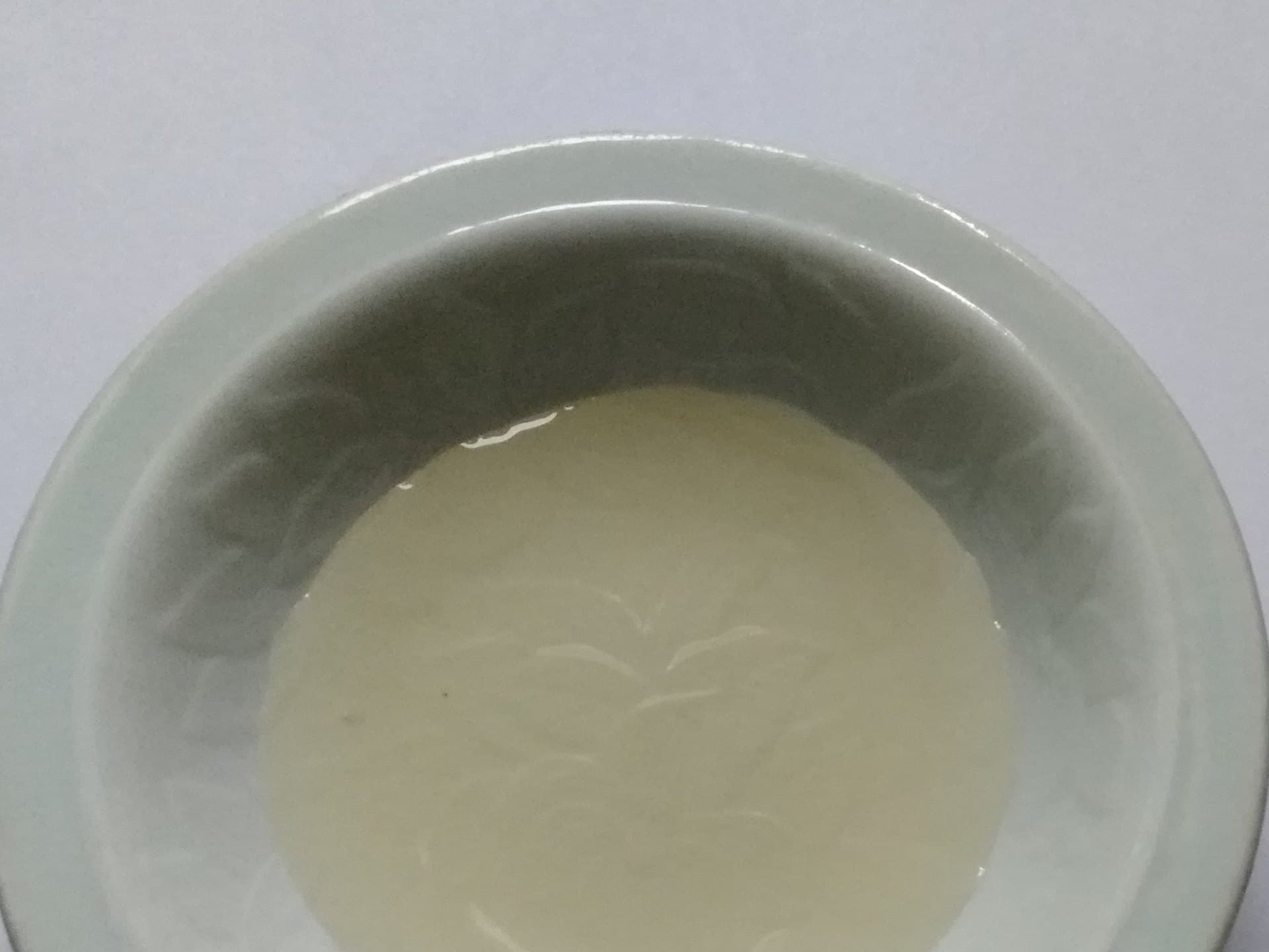 Overhead of pale rice vinegar in a small celadon bowl